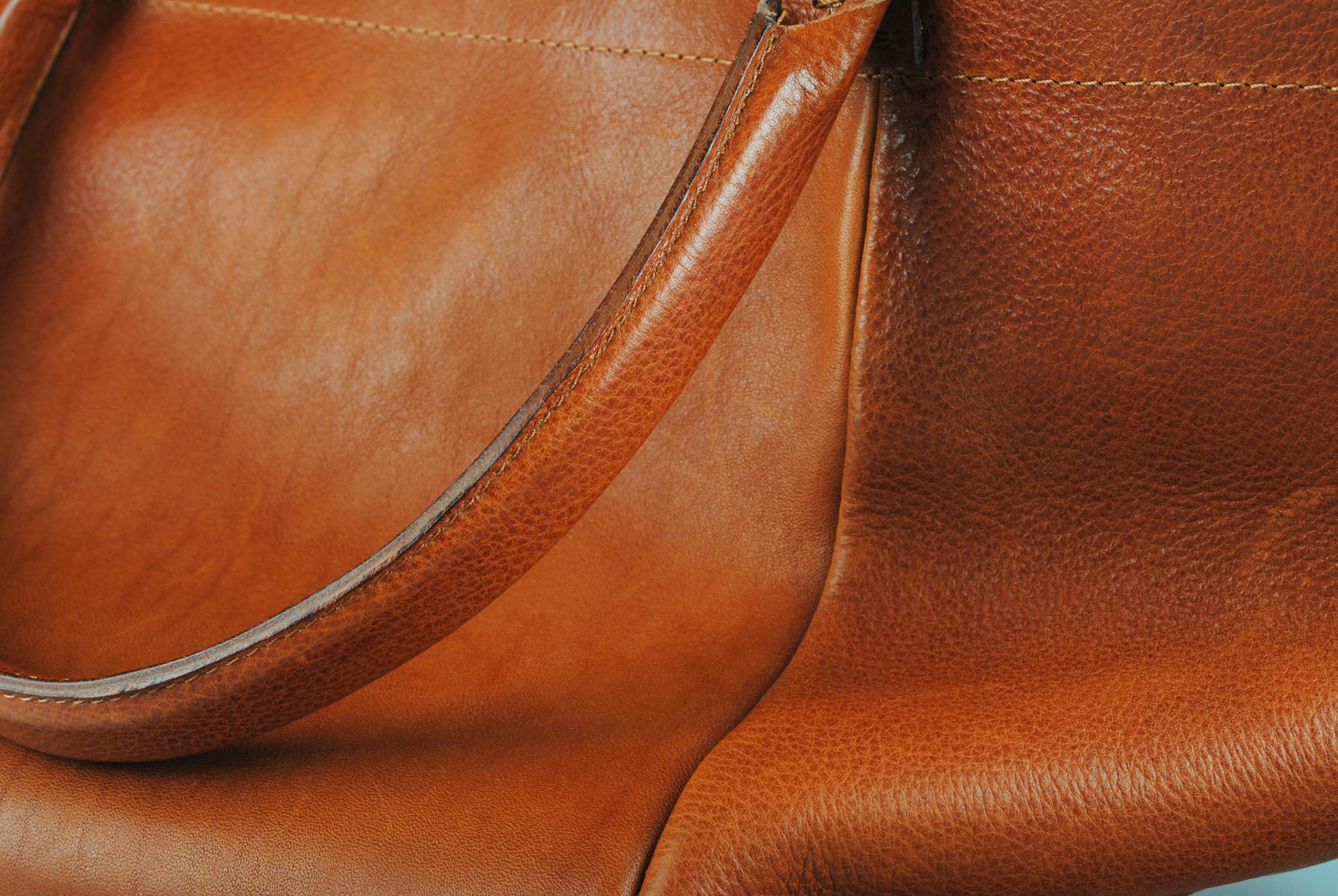 Detail view of a high-quality brown leather bag with smooth texture.