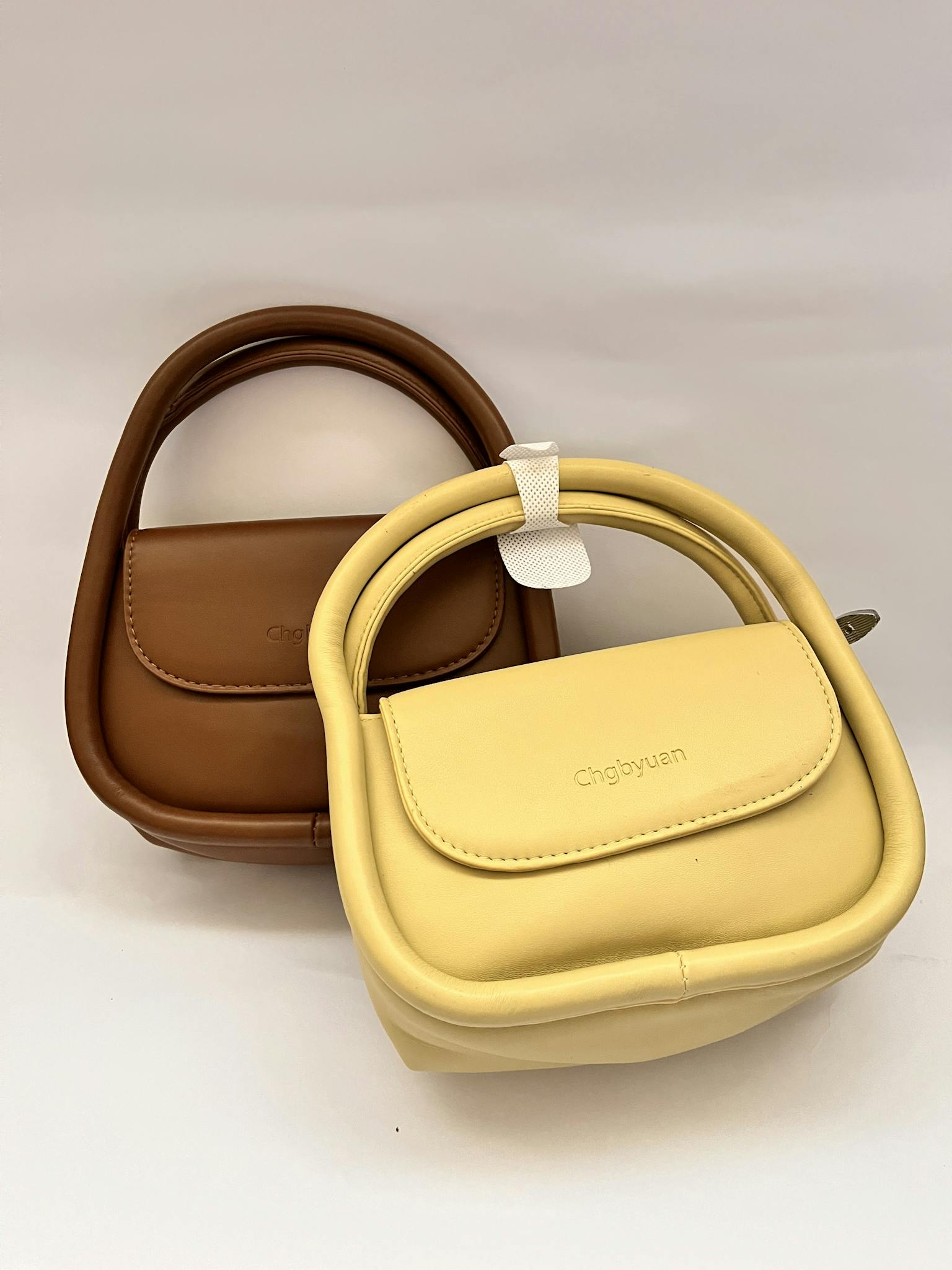 Elegant brown and yellow handbags displayed, showcasing modern leather fashion accessories.