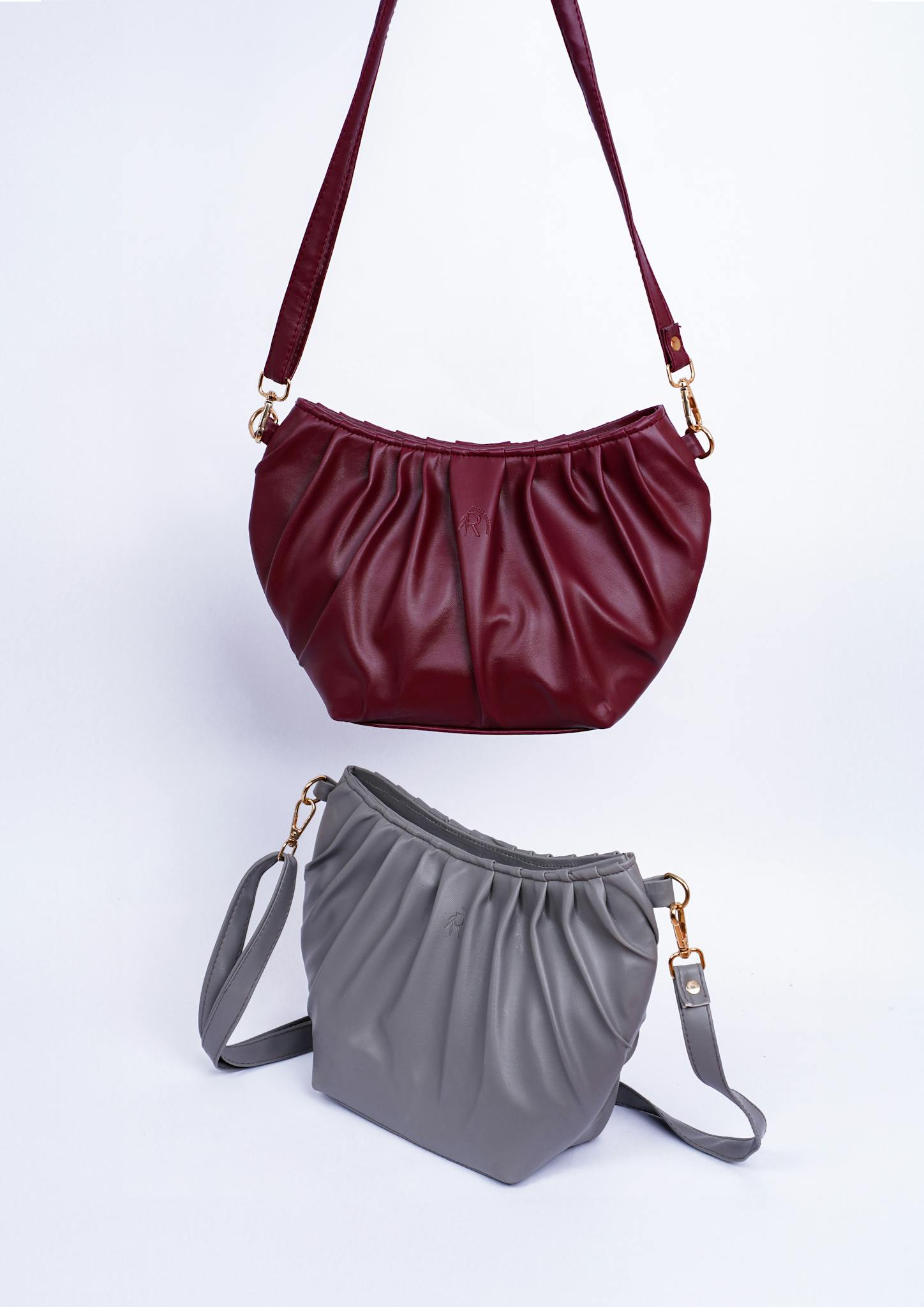 Studio shot of luxury red and gray leather handbags on a white background, showcasing elegance and style.
