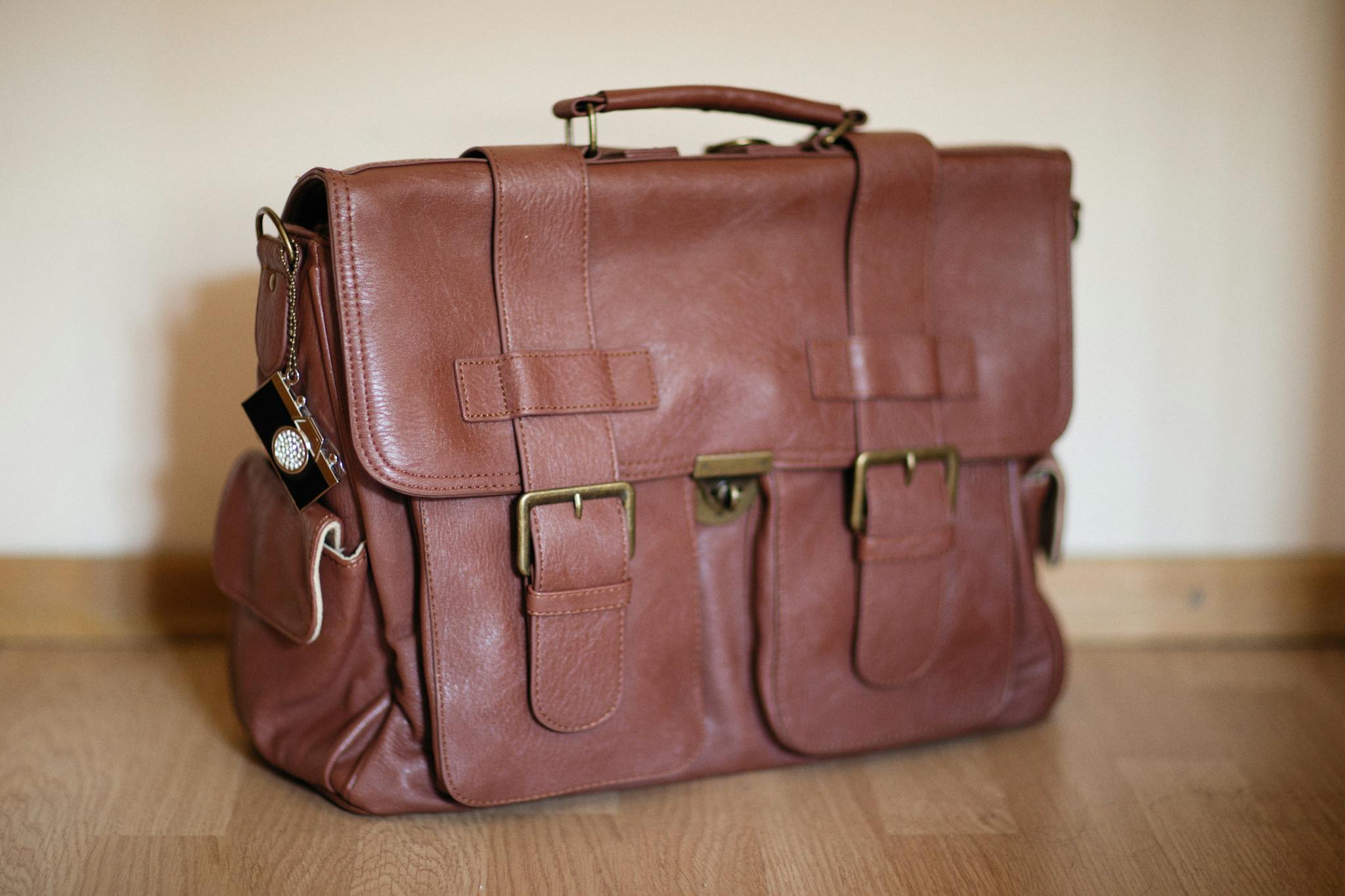 Stylish brown leather satchel on wooden flooring, perfect for travel or business.
